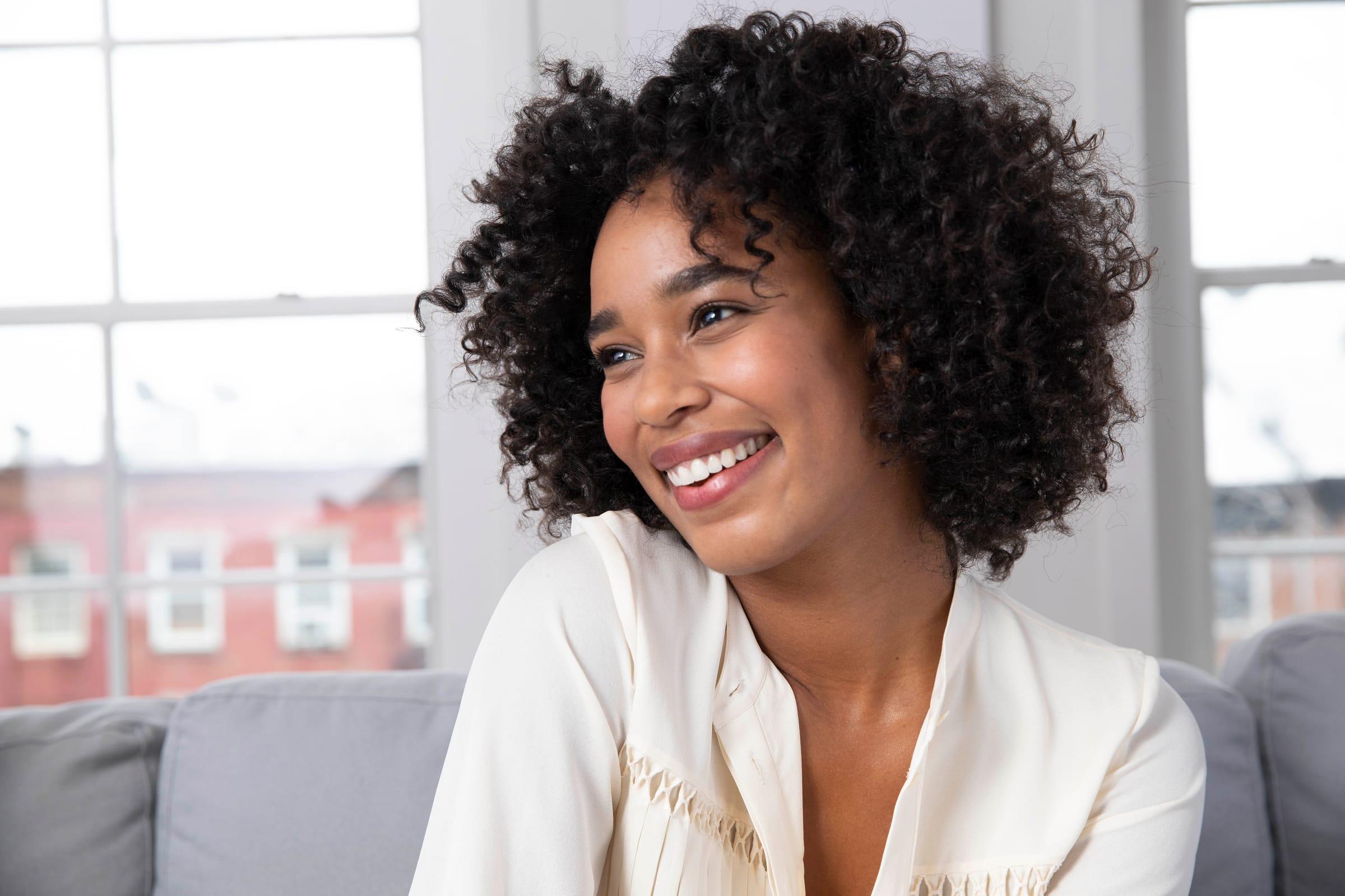 A woman smiling and looking off camera in a bright living room